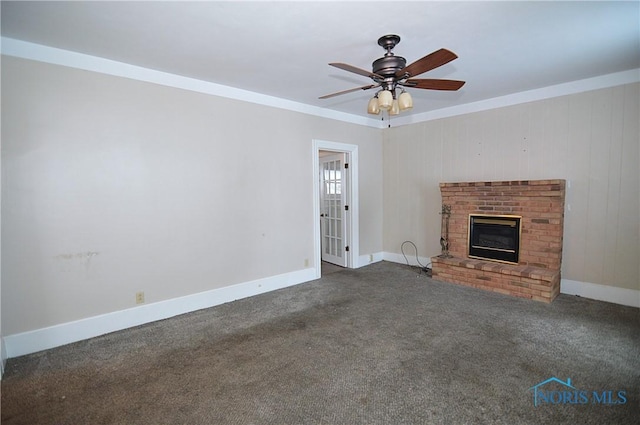 unfurnished living room featuring a brick fireplace, dark carpet, ornamental molding, and ceiling fan