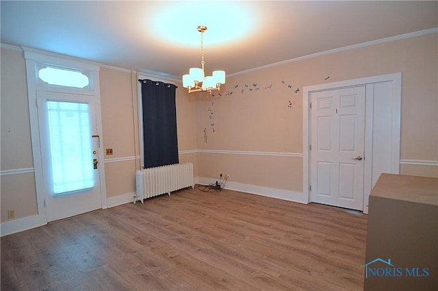 unfurnished dining area featuring a notable chandelier, hardwood / wood-style flooring, radiator, and crown molding