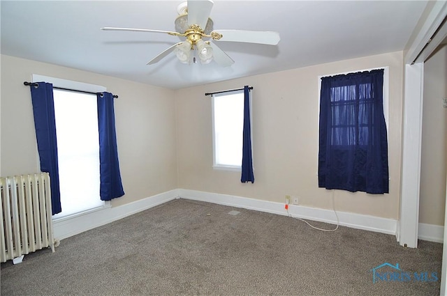 unfurnished room featuring carpet flooring, radiator, and ceiling fan