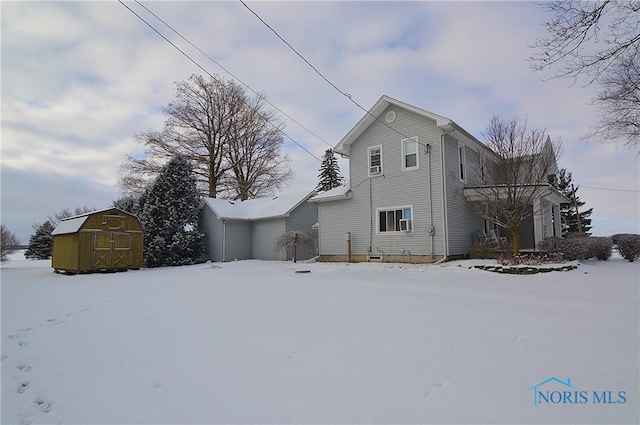 snow covered rear of property featuring a shed