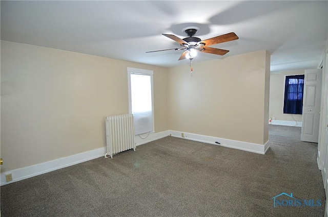 empty room with radiator, dark carpet, and ceiling fan