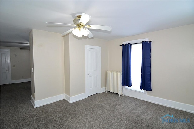 carpeted empty room with ceiling fan and radiator heating unit