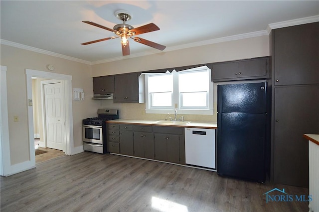 kitchen featuring dishwasher, crown molding, stainless steel gas range, sink, and black fridge