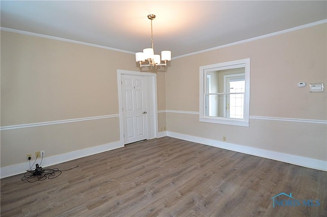 empty room with ornamental molding, hardwood / wood-style flooring, and a chandelier