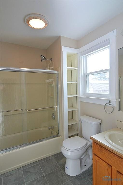 full bathroom with tile patterned floors, toilet, vanity, and shower / bath combination with glass door