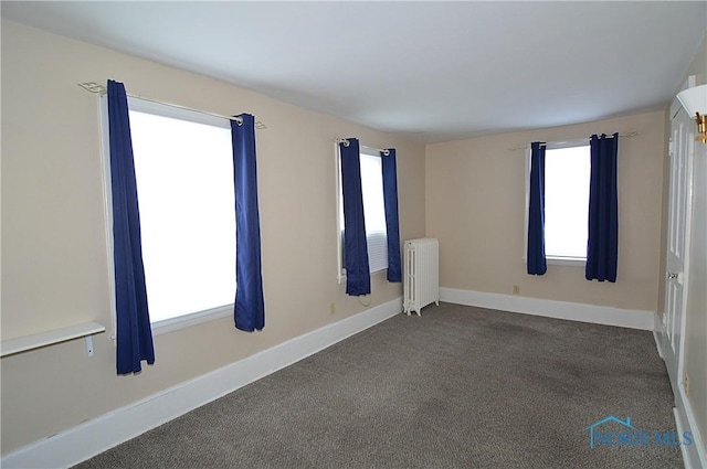 carpeted spare room featuring radiator heating unit