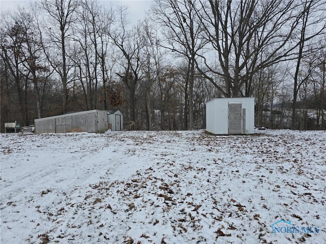 yard covered in snow featuring a shed