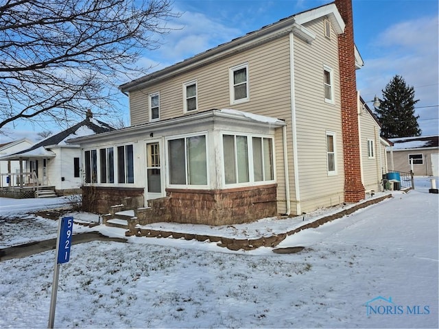 snow covered property featuring a sunroom