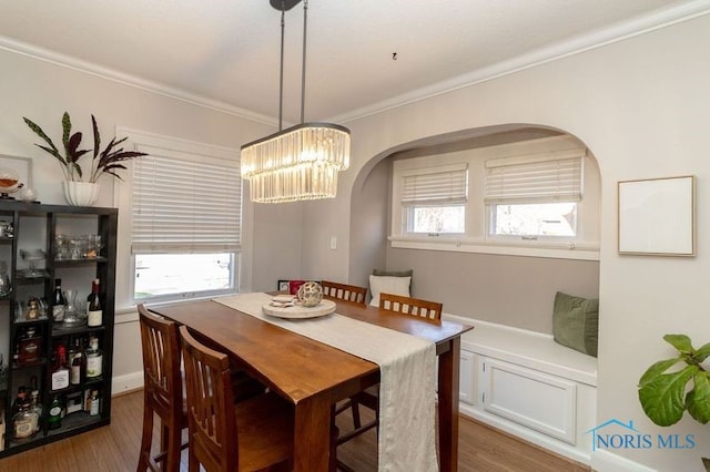 dining area with a wealth of natural light, crown molding, a chandelier, and dark hardwood / wood-style floors