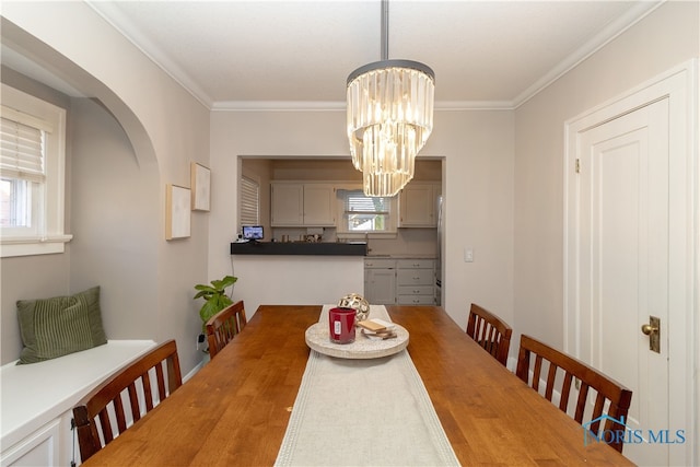 dining space with a wealth of natural light, crown molding, and a notable chandelier