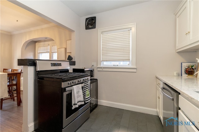 kitchen with ornamental molding, light stone counters, dark hardwood / wood-style flooring, white cabinetry, and stainless steel appliances