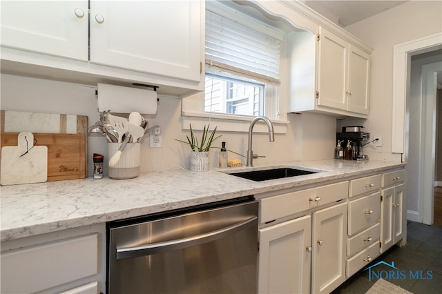 kitchen featuring stainless steel dishwasher, light stone counters, white cabinetry, and sink