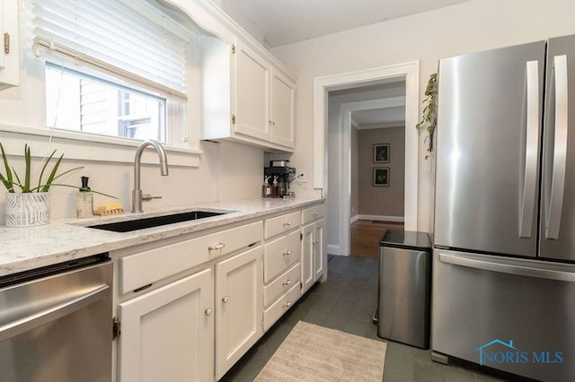 kitchen featuring white cabinets, light stone counters, sink, and stainless steel appliances