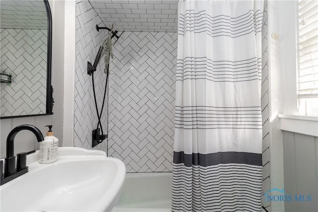 bathroom featuring shower / bathtub combination with curtain and sink