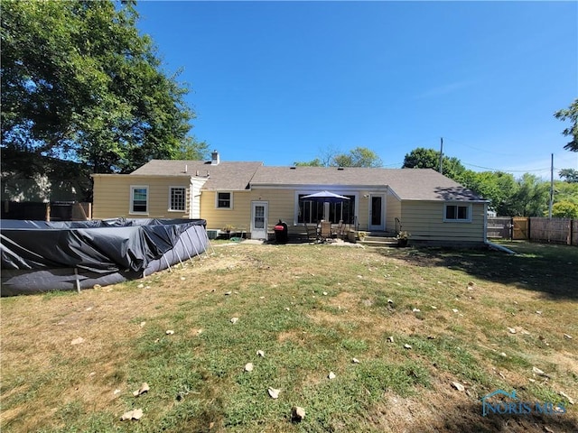 rear view of house with a lawn and a covered pool