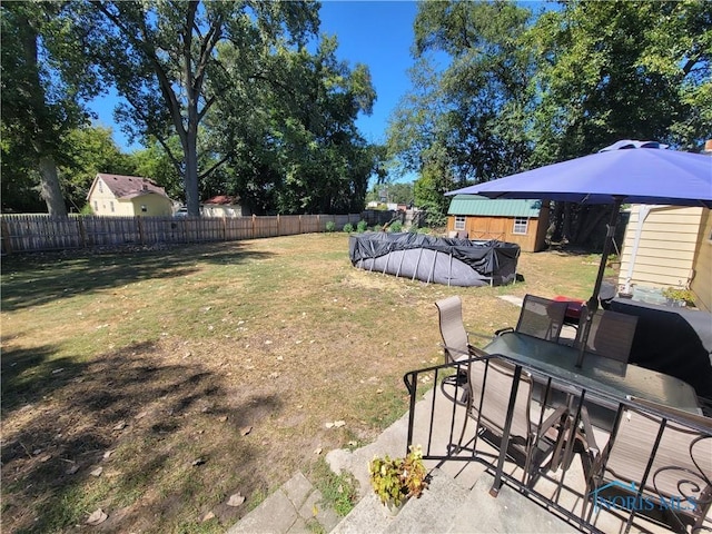 view of yard featuring a covered pool and a storage unit