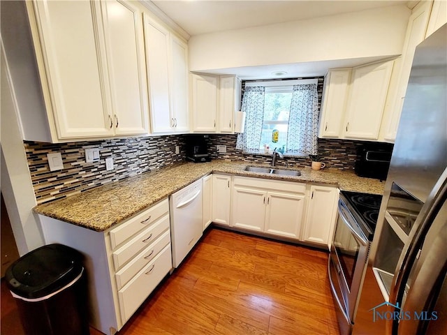 kitchen featuring appliances with stainless steel finishes, light stone counters, white cabinetry, and sink