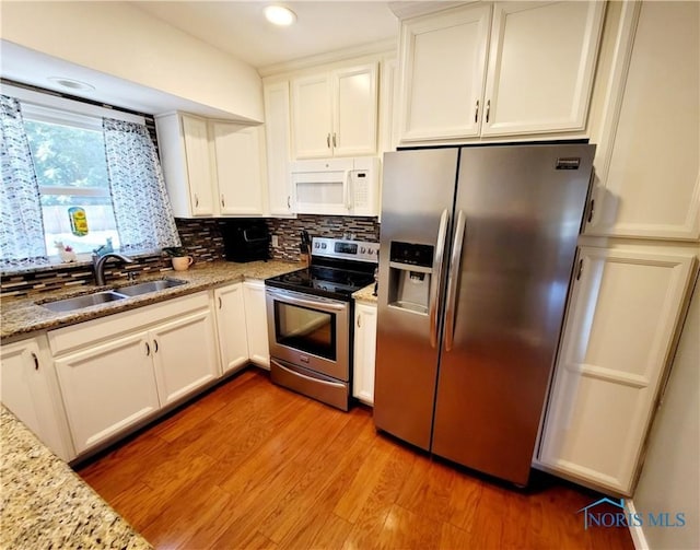 kitchen featuring sink, light hardwood / wood-style floors, light stone counters, white cabinetry, and stainless steel appliances