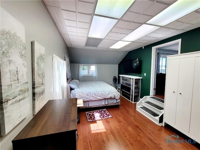 bedroom with hardwood / wood-style floors, vaulted ceiling, and a drop ceiling