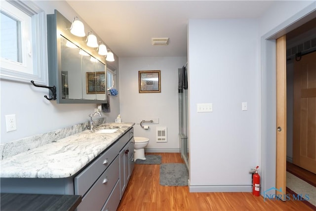 bathroom featuring curtained shower, heating unit, wood-type flooring, toilet, and vanity