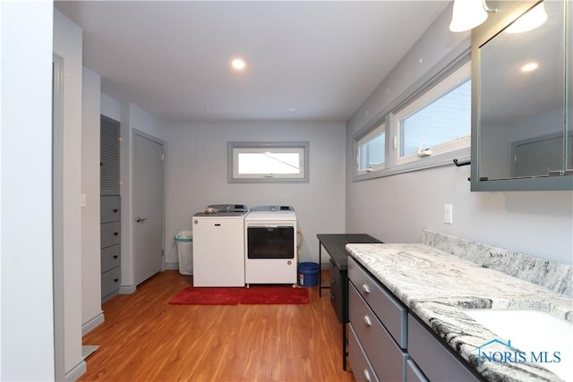 laundry area featuring cabinets, sink, light hardwood / wood-style floors, and washing machine and clothes dryer