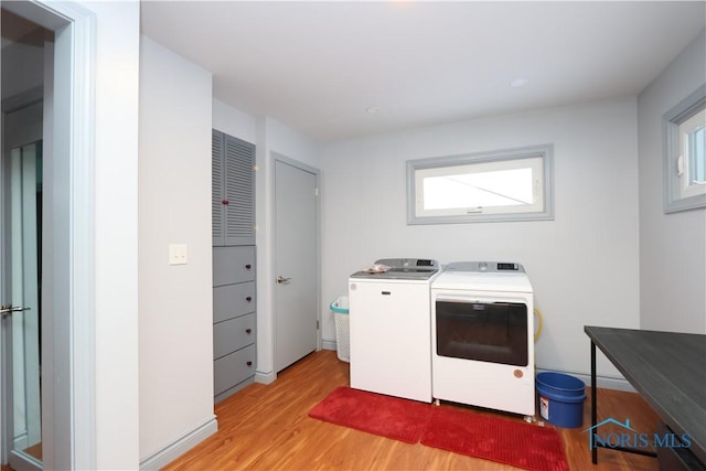 clothes washing area with light hardwood / wood-style flooring, plenty of natural light, and washing machine and clothes dryer