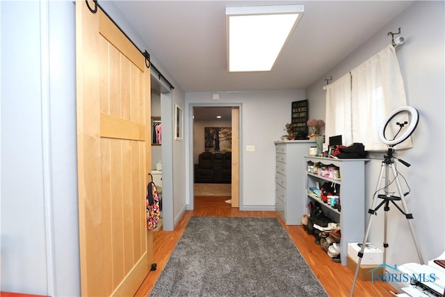 hallway with a barn door and light hardwood / wood-style flooring