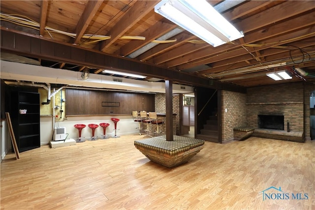 basement with light hardwood / wood-style floors and a brick fireplace