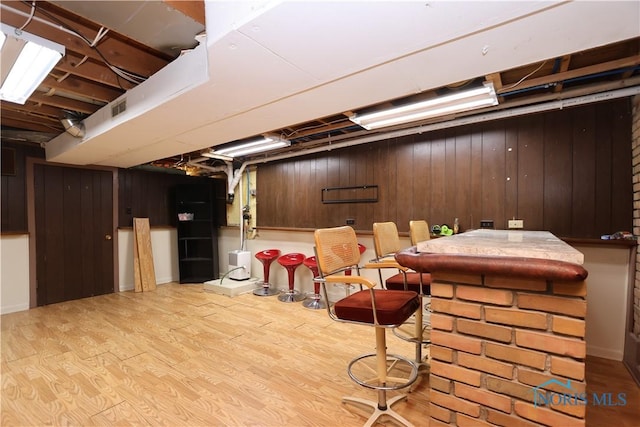 basement featuring light wood-type flooring and wood walls