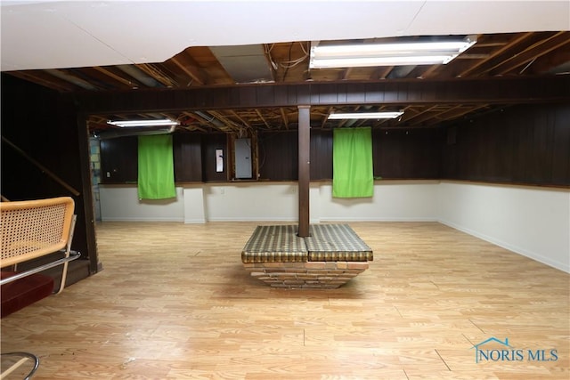 basement featuring electric panel and light hardwood / wood-style flooring