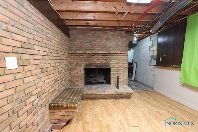 basement featuring light hardwood / wood-style flooring and a brick fireplace