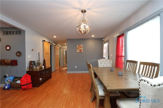 dining room featuring a chandelier, a barn door, and light hardwood / wood-style flooring