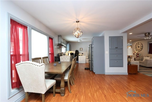 dining space with hardwood / wood-style floors and ceiling fan with notable chandelier