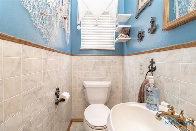 bathroom featuring sink, toilet, and tile walls