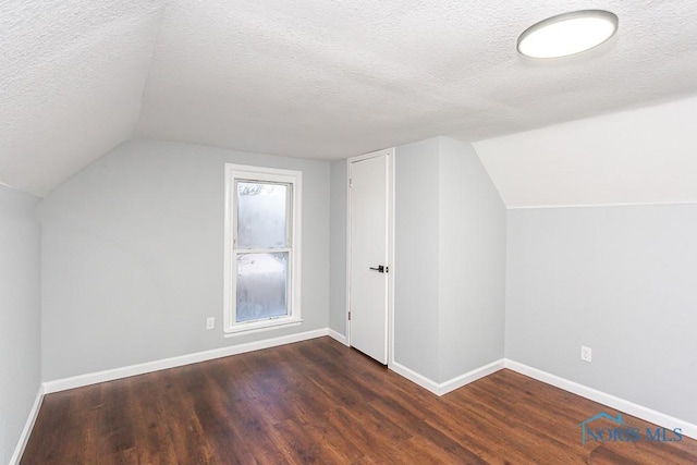 bonus room featuring dark wood-type flooring, vaulted ceiling, and a textured ceiling