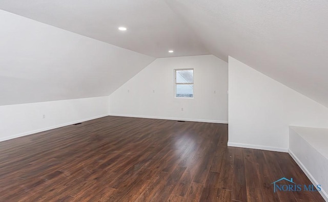 bonus room with dark wood-type flooring and lofted ceiling