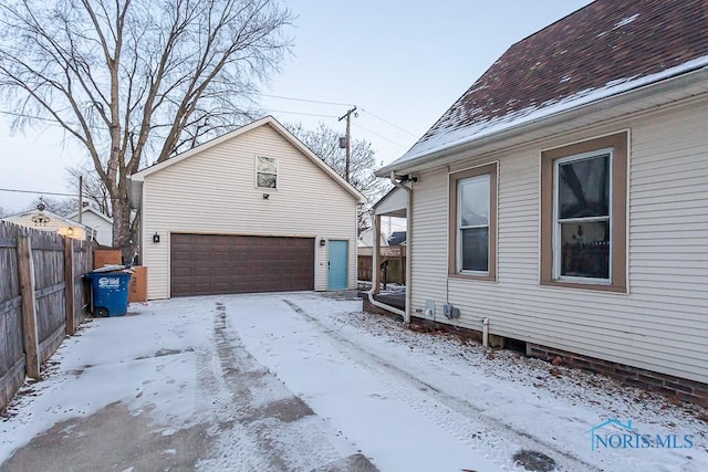 snow covered property featuring a garage and an outbuilding