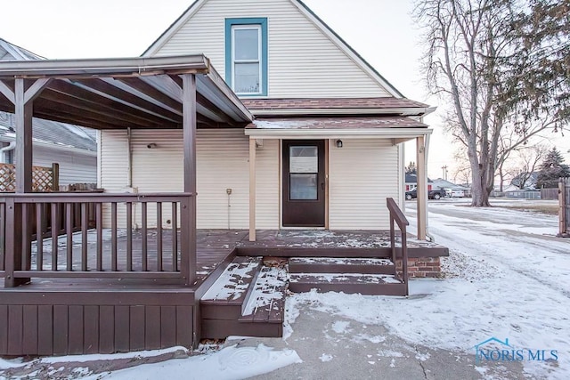 snow covered property entrance with covered porch