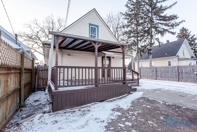 snow covered rear of property featuring covered porch