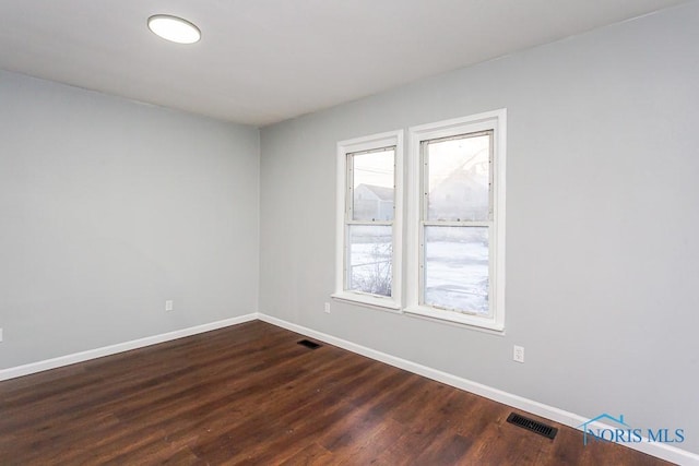 empty room featuring plenty of natural light and dark hardwood / wood-style floors