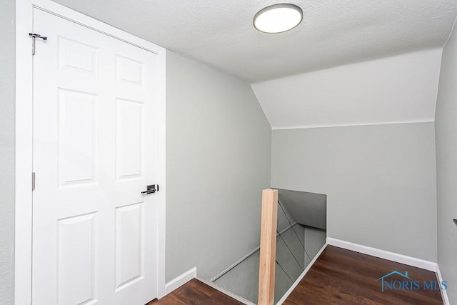 stairs featuring lofted ceiling, hardwood / wood-style floors, and a textured ceiling