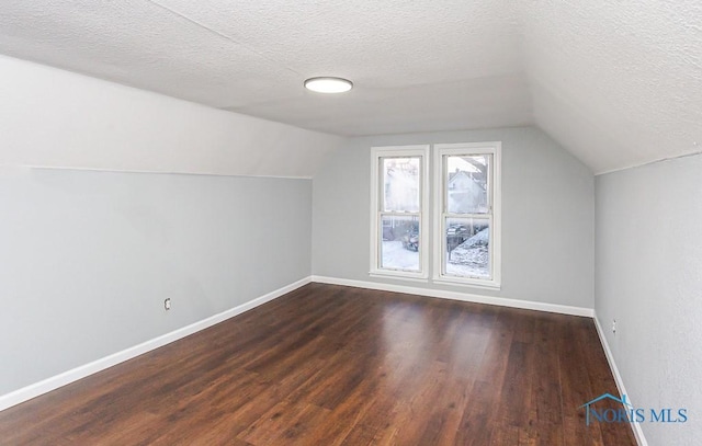 bonus room with vaulted ceiling, dark wood-type flooring, and a textured ceiling