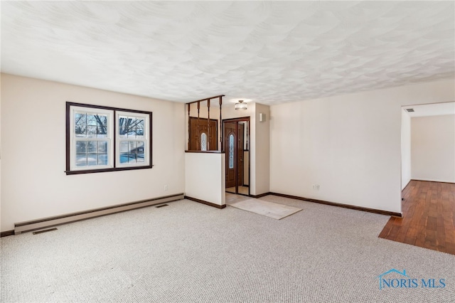 unfurnished living room featuring a textured ceiling, baseboard heating, and light carpet