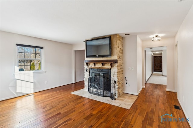 unfurnished living room featuring a stone fireplace and light hardwood / wood-style flooring