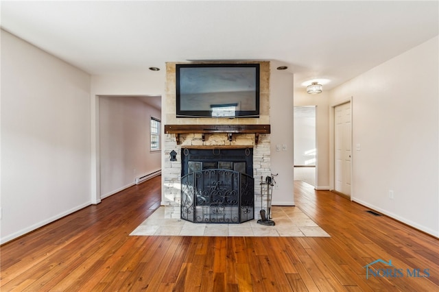 unfurnished living room with a fireplace, light hardwood / wood-style floors, and a baseboard radiator