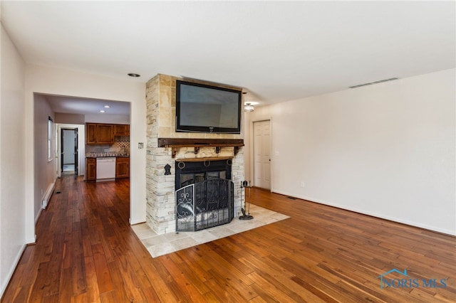 unfurnished living room with hardwood / wood-style floors and a stone fireplace