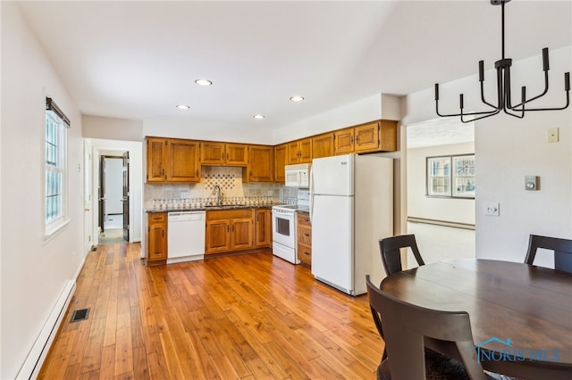 kitchen featuring sink, hanging light fixtures, an inviting chandelier, baseboard heating, and white appliances