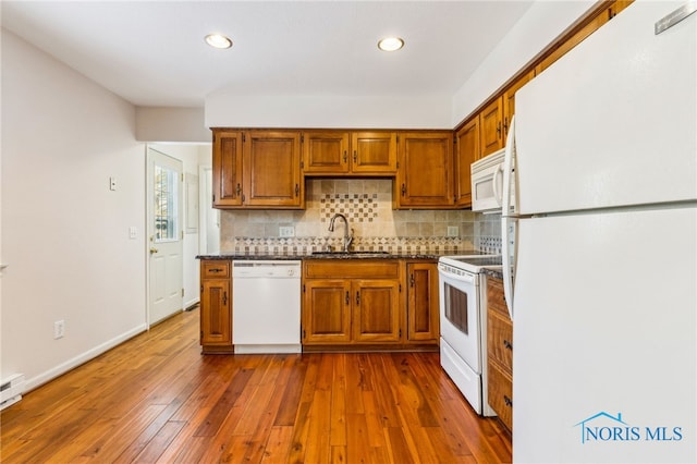 kitchen featuring hardwood / wood-style floors, backsplash, white appliances, and sink