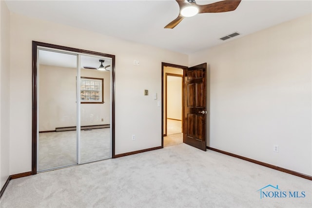 unfurnished bedroom with a closet, a baseboard radiator, ceiling fan, and light colored carpet