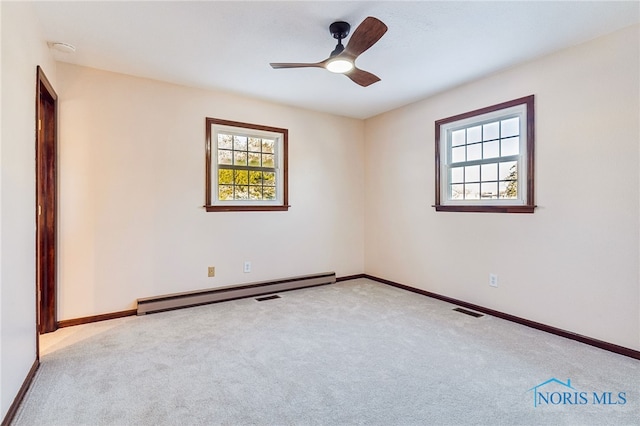 unfurnished room featuring a wealth of natural light, ceiling fan, light carpet, and a baseboard heating unit